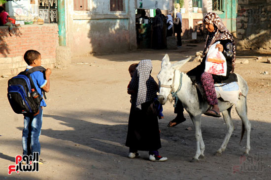 فتاة تقل أختها إلى المدرسة على حمار